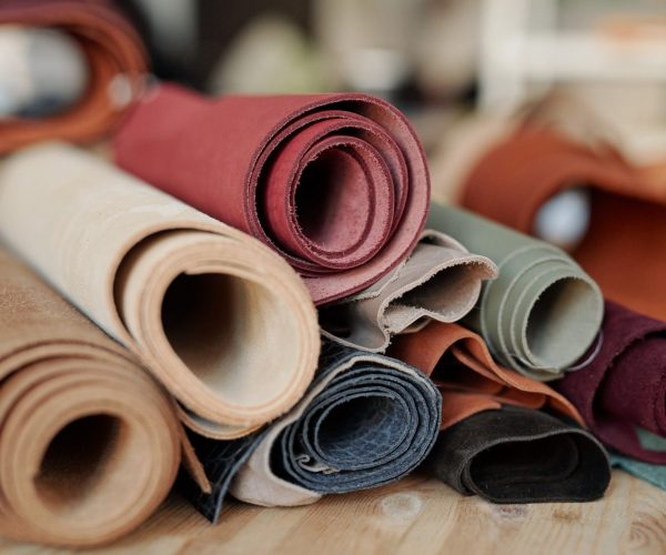 Collection of rolled suede and leather of various colors lying on wooden table